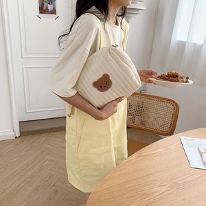 Close-up of quilted ivory baby stroller bag with soft 3D brown bear embroidery detail