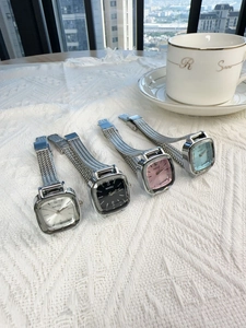 Collection of four elegant square dial ladies watches with silver mesh straps on fabric
