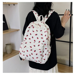Detail of the corduroy backpack with strawberry print on an cream-white surface