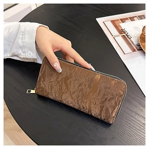 Detail shot of brown long zip wallet with pleated texture held in hand for daily use