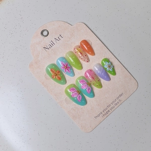 Detail of handmade 3D floral almond nails with candy gradient and gold bead accents