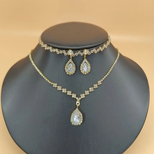 Close-up of golden bridal jewelry set with pear-shaped cubic zirconia on black mannequin