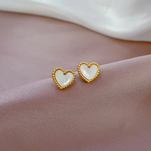 Macro shot of titanium steel heart studs with gold bead borders and white shell inlay