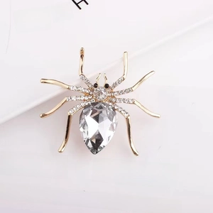 Macro shot of spider brooch with gold metal legs, rhinestones, and large teardrop crystal
