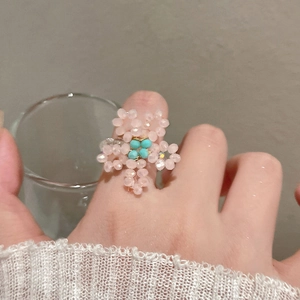 Détail d'une bague fleur en perles faite main avec cristaux roses et centre bleu