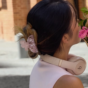 Pince à cheveux papillon rose en acétate portée sur une coiffure demi-attachée élégante