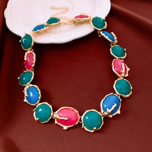 Detail of vintage gold necklace with pink, turquoise, and blue resin oval pendants