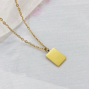 Close-up of minimalist gold-plated rectangular tag pendant on a delicate link chain