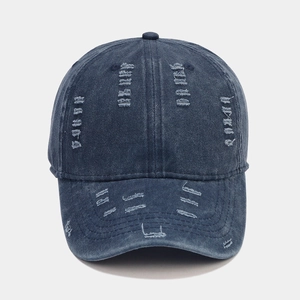 Detail of distressed navy blue denim baseball cap with vintage frayed holes and texture