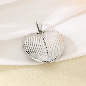 Macro shot of silver heart pendant with textured stripes on elegant silk fabric