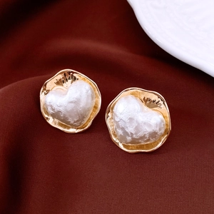 Détail macro de boucles d'oreilles cœur en perles dorées avec texture baroque