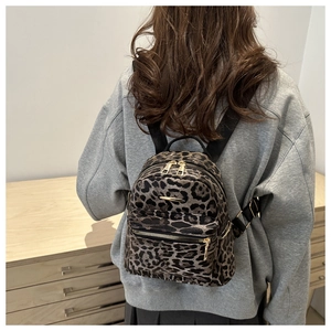 Detail of trendy leopard print mini backpack with golden zippers shown on a model's back