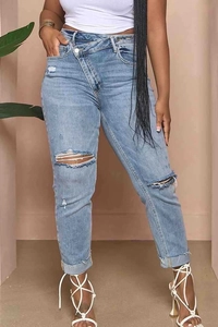 Detail of high waist cross-over fly and distressed ripped knees on light blue denim jeans