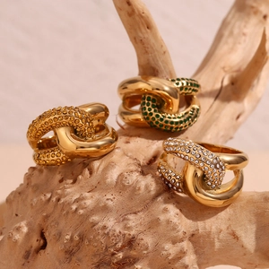 Detailed macro view of 18K gold plated knot rings with colorful zircon stones on wood