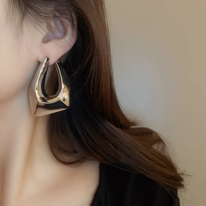 Gros plan de boucles d'oreilles géométriques argentées portées par un mannequin de profil