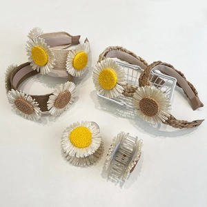 Set of woven raffia headbands and daisy claw clips in khaki colors on white background