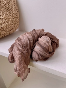 Detailed close-up of brown gradient wrinkled scarf with soft textured fabric and pleats