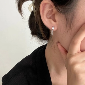 Close-up of silver chain earrings with rectangular clear cubic zirconia on ear