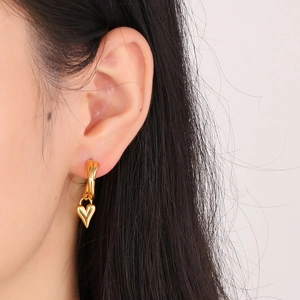 Minimalist gold heart dangle earrings in titanium steel shown on a model