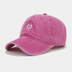Close-up of rose pink washed cotton baseball cap with white heart embroidery detail