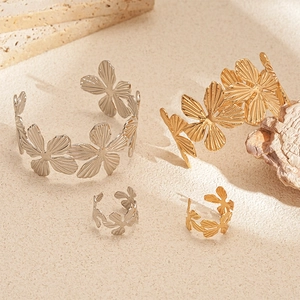 Golden and silver textured floral open bracelets and rings on a natural stone base