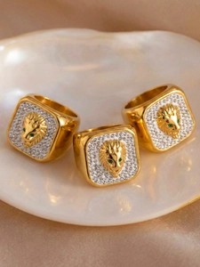Macro view of gold-plated lion head rings with sparkling crystals and green eyes detail