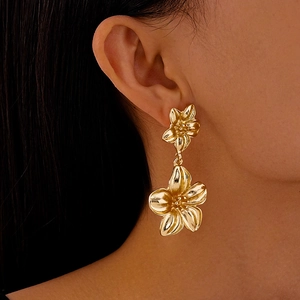 Nahaufnahme goldener, geschichteter Blumenohrringe am Model mit 3D-Metallic-Blumendesign