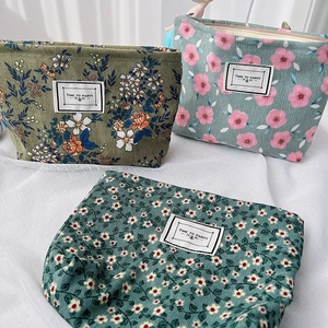 Detailed shot of three corduroy cosmetic bags featuring floral patterns and party labels