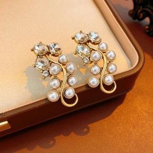 Detail of vintage gold-tone earrings with white pearls and crystals in a luxury jewelry box