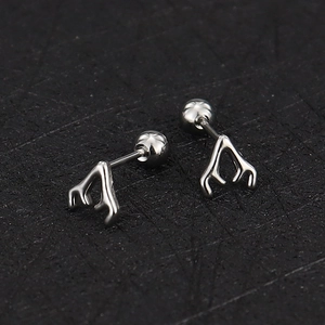 Close-up of silver antler cartilage earrings with screw ball backs on black texture