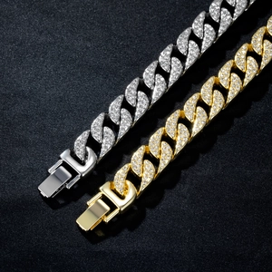 Gros plan de bracelets cubains or et argent avec strass brillants sur tissu texturé noir