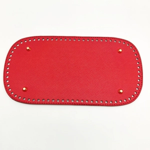 Macro shot of red PU leather bag base with golden metal feet and pre-punched holes