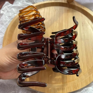 Detail of amber tortoiseshell hair claw clip opening with metal spring mechanism