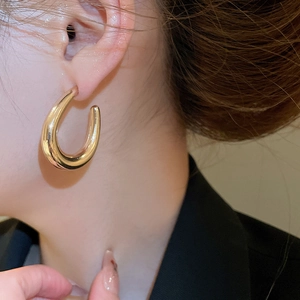 Close-up of polished gold U-shaped earrings on model for a minimalist fashion look