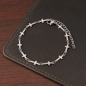 Silver stainless steel cross link bracelet with lobster clasp on leather background