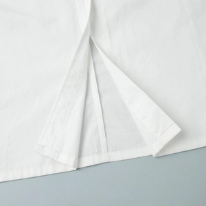 Close-up of side slit design on white cotton sleeveless long shirt dress with neat stitching