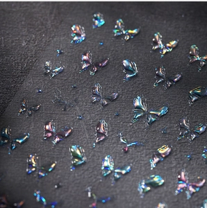 Macro shot of 3D iridescent butterfly nail stickers with embossed texture on dark surface