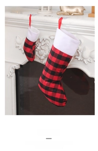 Red and black plaid Christmas stockings in two sizes hanging on a white mantel fireplace
