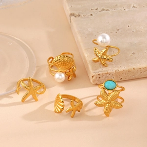 Golden ocean shell and starfish ring set with pearls and blue gemstones on stone base