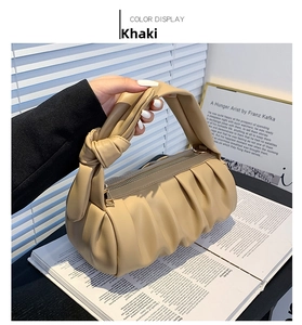Detail view of khaki pleated cloud bag with elegant knot handle and gold zipper closure
