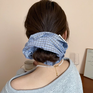 Close-up of blue checkered hair scrunchie with elegant pearl necklace on model back