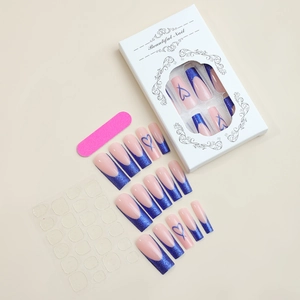 Detail of long coffin press-on nails with blue glitter tips and heart patterns in a box