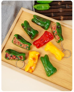 Realistic PVC stuffed green pepper keychain with detailed meat texture in a wooden tray