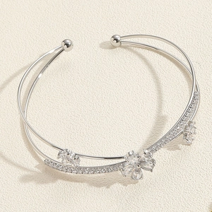 Macro shot of silver dual-line open bangle with three zircon flowers and crystal pavé details