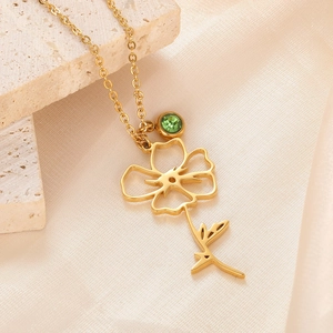 Detail of 18k gold-plated floral pendant necklace with a green gemstone on silk