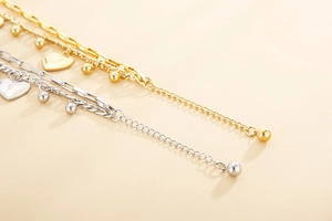 Detail of beaded heart bracelet featuring polished metallic finish and adjustable chain