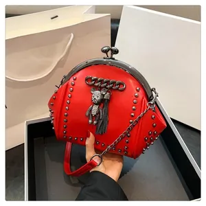 Detail of red rivet shell bag featuring crystal bear charm and metallic fringe tassels
