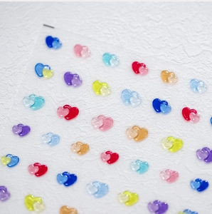 Macro detail of colorful 3D heart-shaped nail art stickers with glossy texture