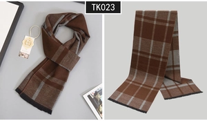 Macro detail of men's wool scarf featuring classic brown plaid texture and fringe edges