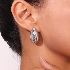 Macro shot of silver teardrop earring with embedded white rhinestones on human ear